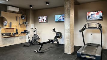 A gym with treadmills, stationary bikes, and a wall-mounted TV.