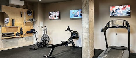 A gym with treadmills, stationary bikes, and a wall-mounted TV.