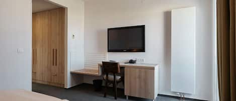 Una habitación de hotel con cama, escritorio, silla, televisor y armario.
