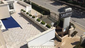 A hotel entrance with a tiled patio, a staircase, and a gate.