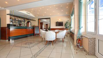 Un hall de hotel con mostrador de recepción, zona de estar y bar.