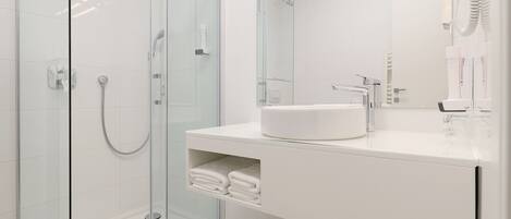 A modern bathroom with a glass-enclosed shower, a white sink, and a large mirror.