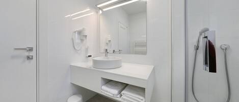 A modern bathroom with a white sink, mirror, and shower.