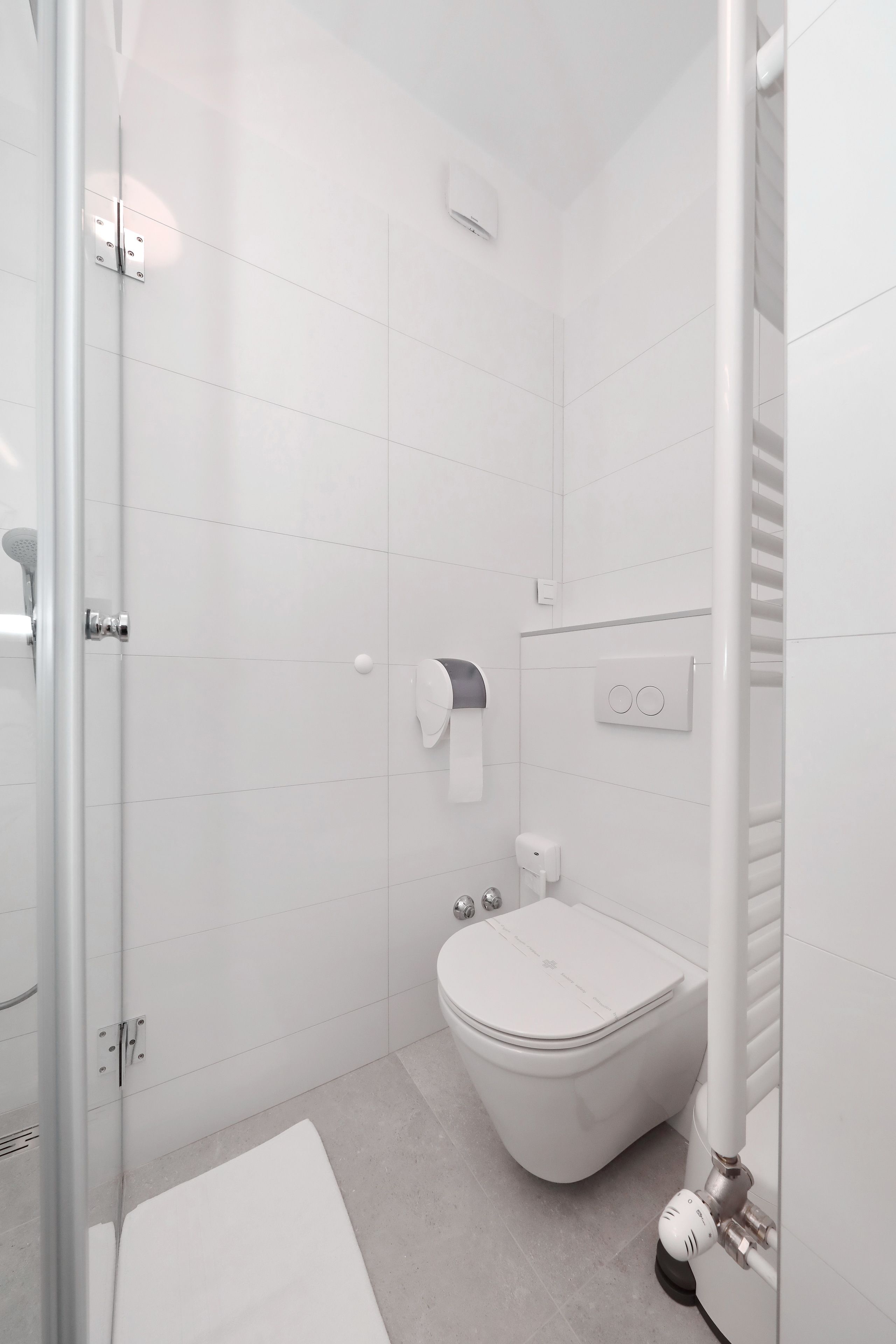 A modern bathroom with a toilet, a shower, and a glass-enclosed shower area.