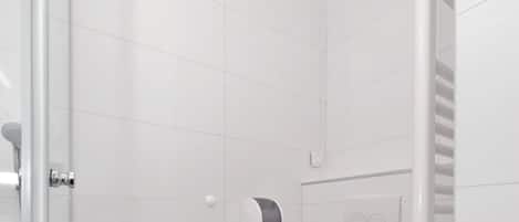 A modern bathroom with a toilet, a shower, and a glass-enclosed shower area.