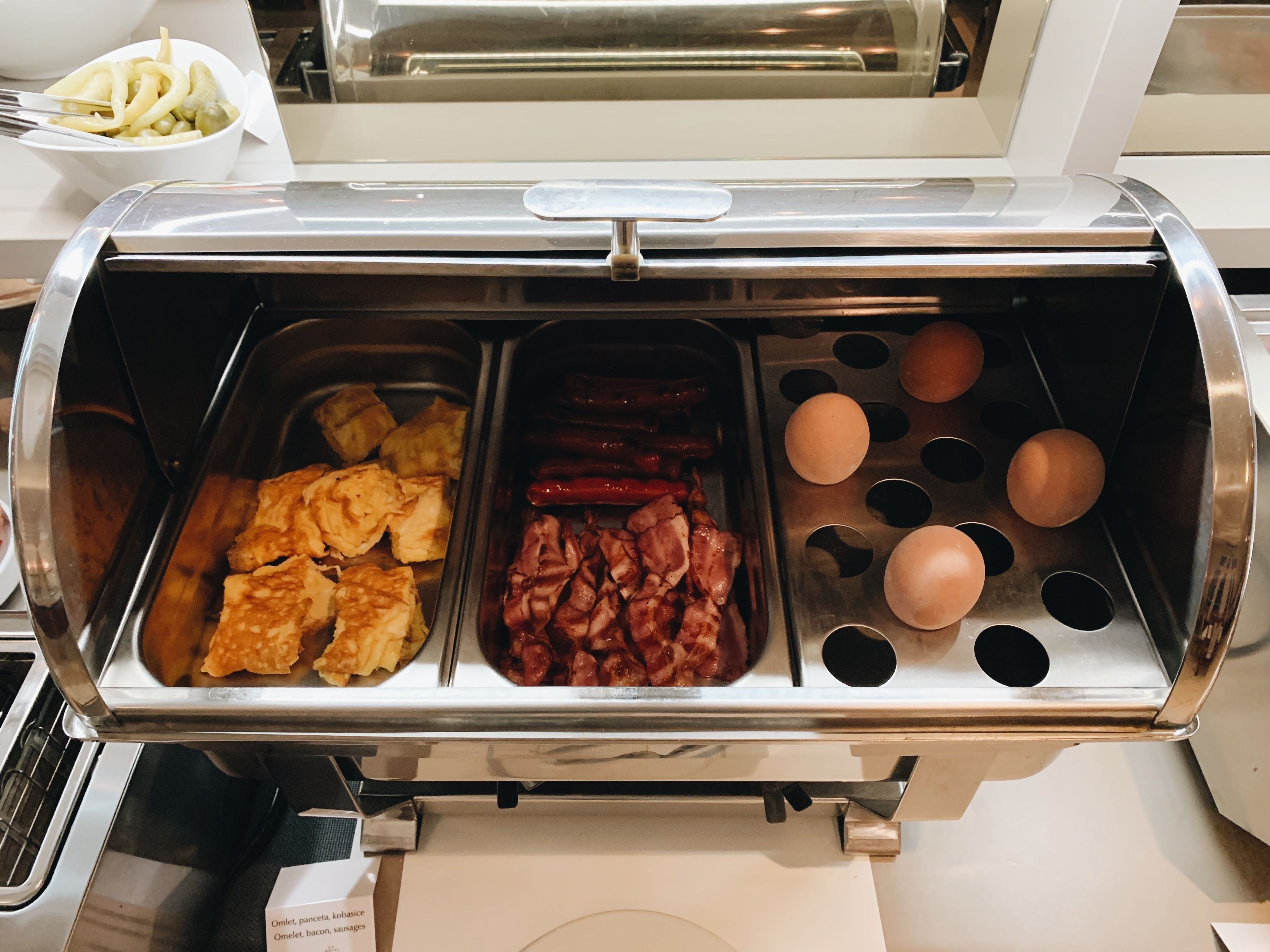 A buffet with various food items including omelets, pancakes, and sausages.