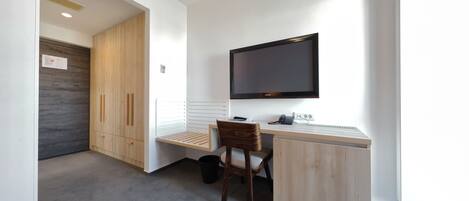 A modern office space with a desk, chair, and a mounted flat-screen TV.