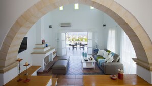 An open-plan living area with a dining area, a sofa, a coffee table, and a TV mounted on the wall. - Protaras Saint Elias Village (Paralimni)