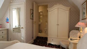 A bedroom with a bed, a wardrobe, a chair, and a bedside table with a lamp.