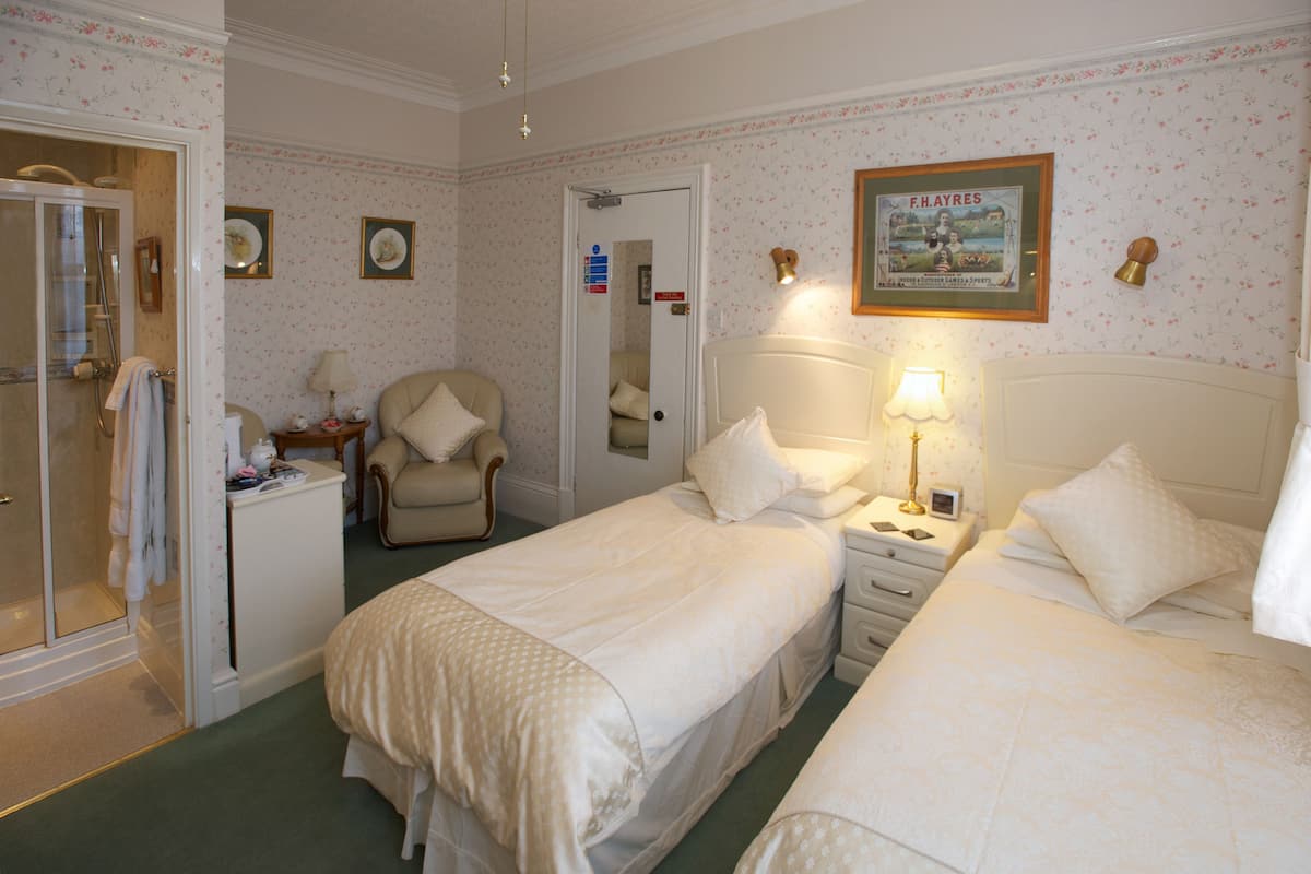 A hotel room with two beds, a chair, a desk, and a mirror.