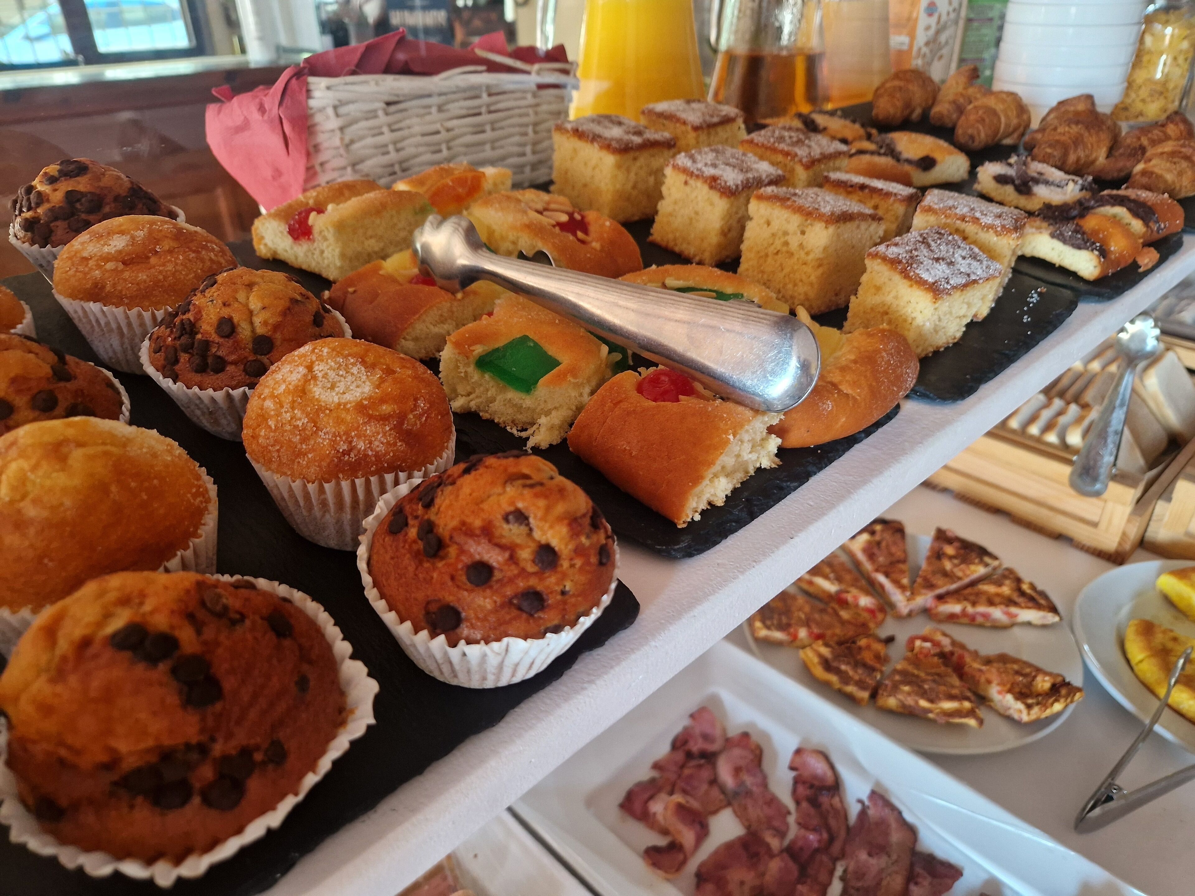 A buffet with various baked goods including muffins, cakes, and pastries.