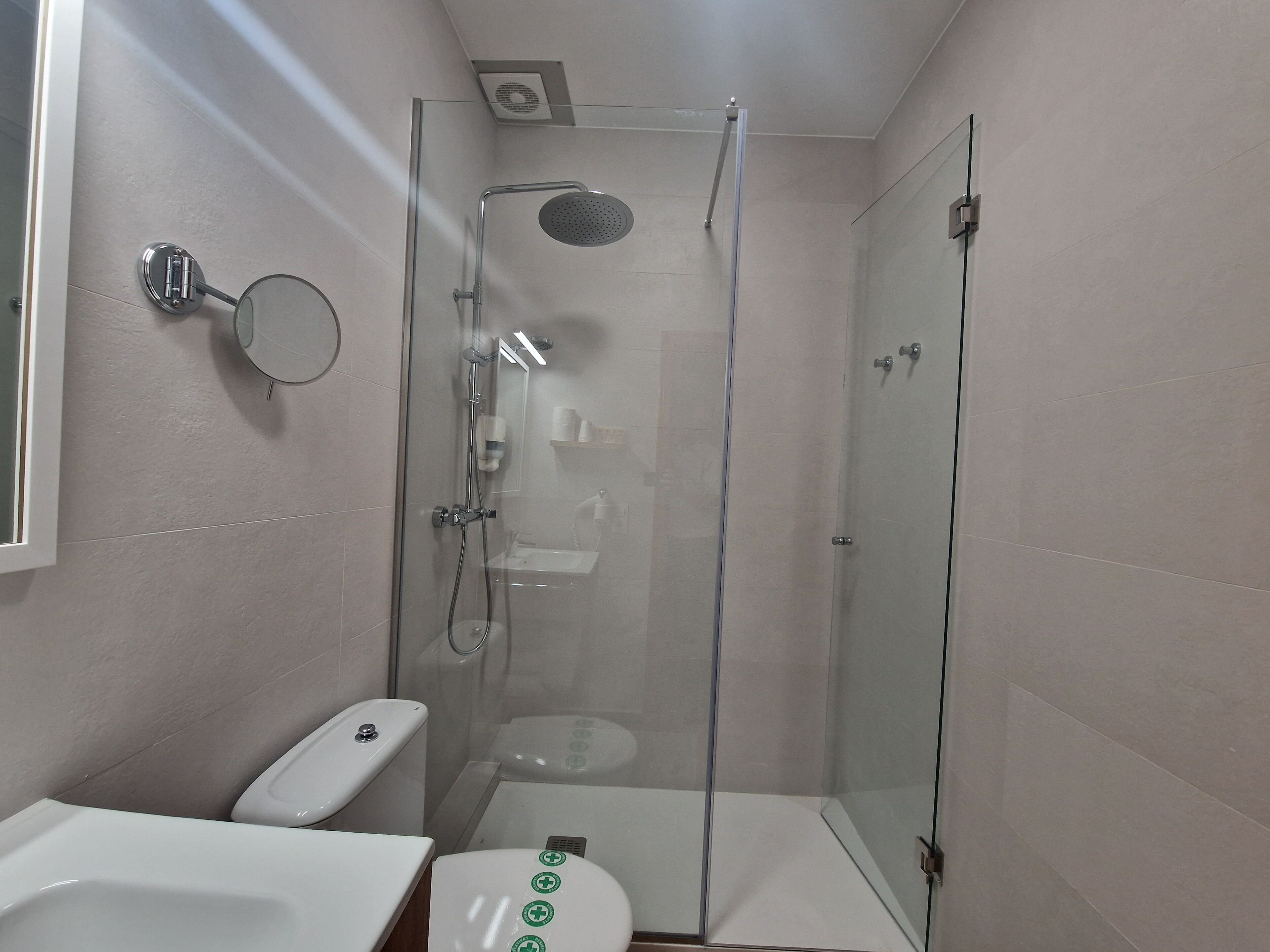 Ein modernes Badezimmer mit einer begehbaren Glasdusche, einer Toilette und einem Waschbecken.