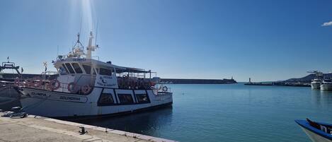 A docked boat named "OLIMPIA" with lifebuoys and a lifebuoy on the deck.