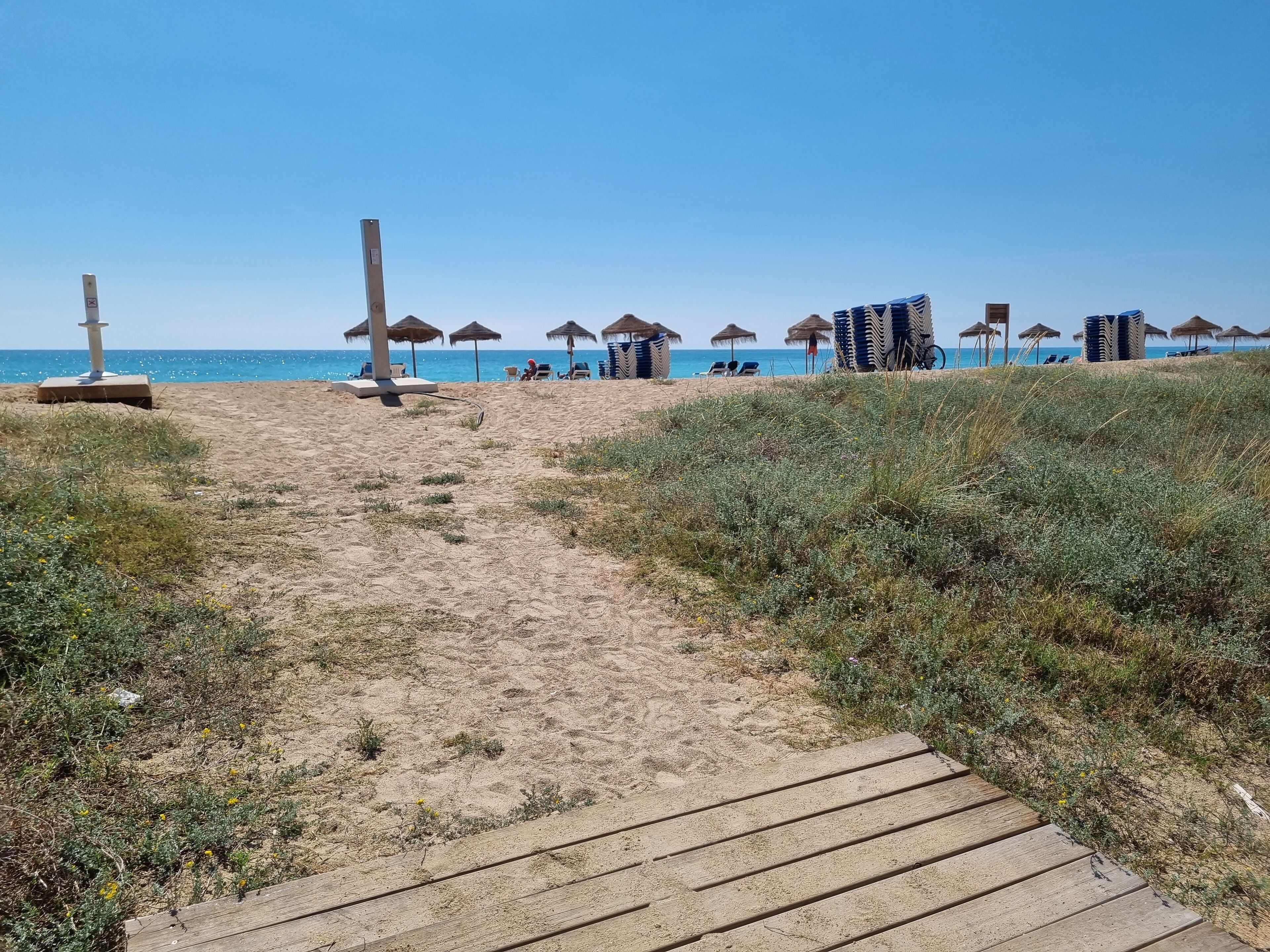 Uma trilha na praia que leva a guarda-sóis e espreguiçadeiras.