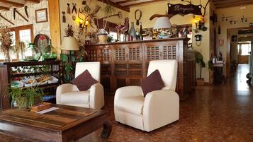 A cozy lobby with two white armchairs, a wooden coffee table, and a reception desk.