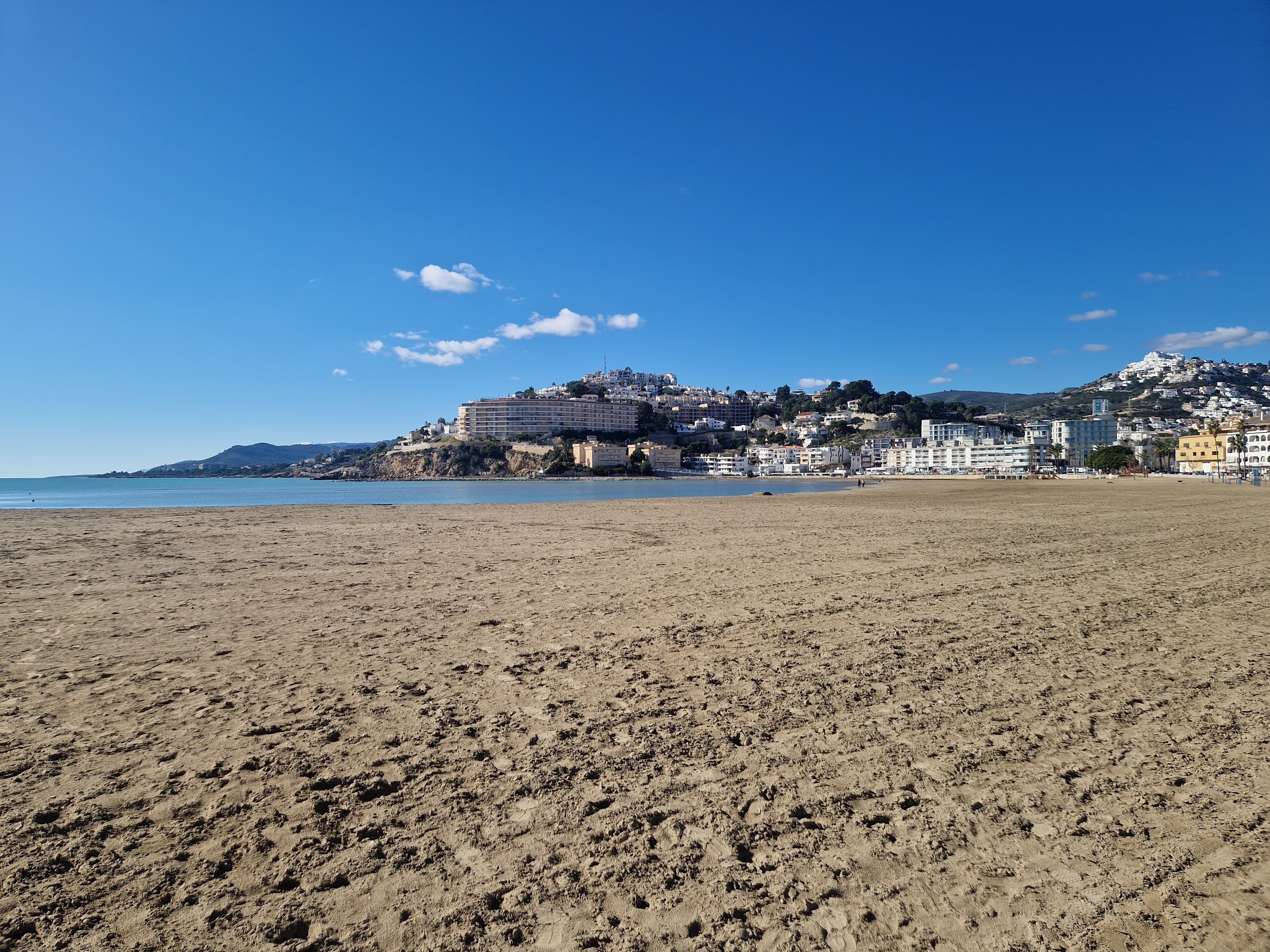 A beach with a large building complex in the background.