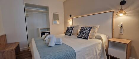 A modern bedroom with a large bed, bedside tables, a mirror, and a wardrobe.