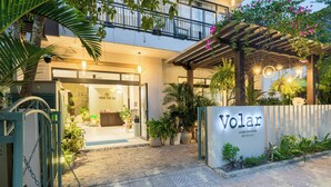 A hotel entrance with a sign reading "Volar," a covered outdoor area with plants, and a paved walkway leading to the entrance. - Volar Hoi An (Da Nang)