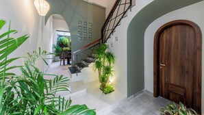 A modern staircase with a wooden finish, a metal railing, and a potted plant at the bottom. - Volar Hoi An (Da Nang)