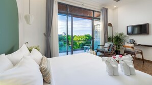 A hotel room with a large bed, a balcony with a view, a TV, and a coffee table. - Volar Hoi An (Da Nang)