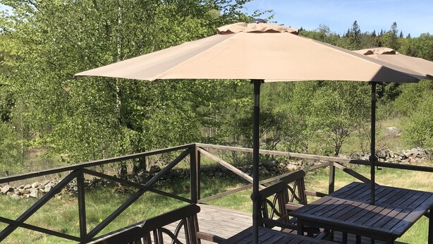 A wooden deck with picnic tables and benches, surrounded by greenery and a clear sky. - Ullstorps Stugor (Hoor)
