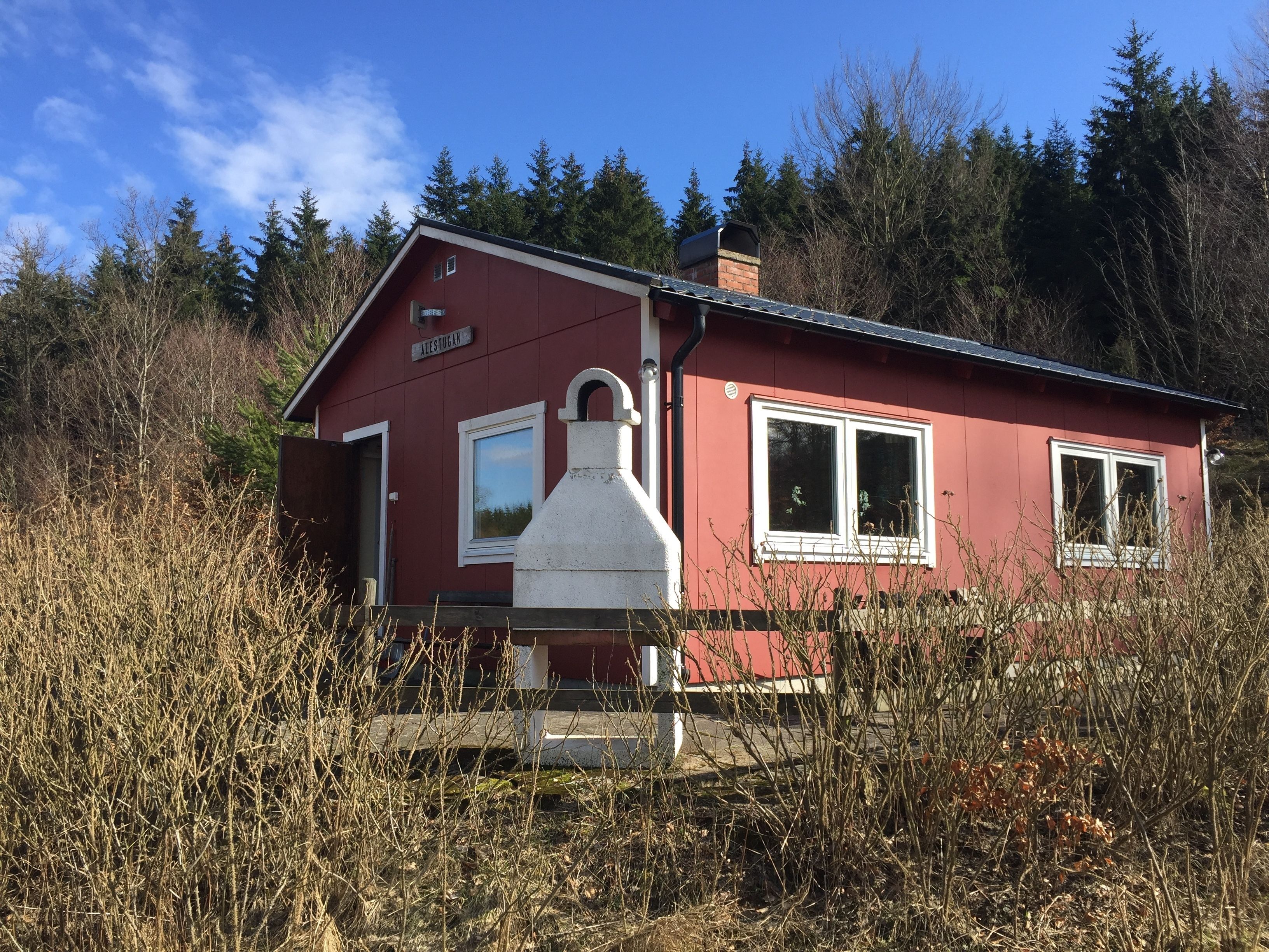A red cabin with a chimney, a window, and a door.