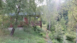 A forested area with a wooden bench and a red building in the background. - Ullstorps Stugor (Hoor)