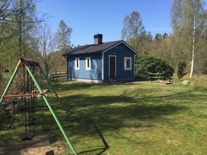 A blue house with a chimney, surrounded by a grassy yard and trees.