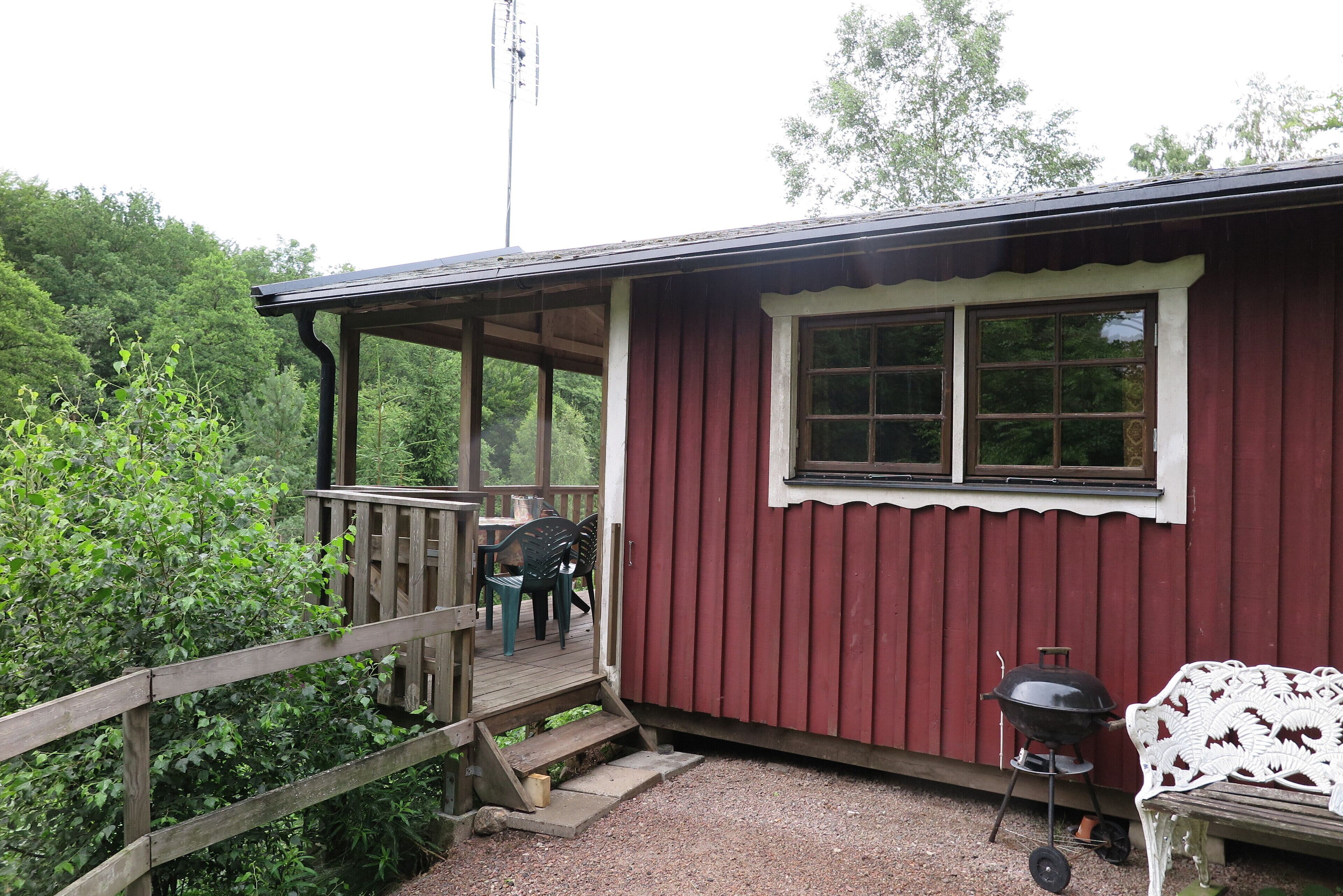 A wooden deck with a covered seating area, a barbecue grill, and a bench.
