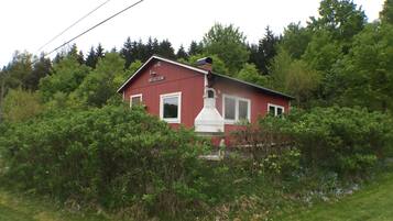 A red house with a chimney, surrounded by dense greenery.