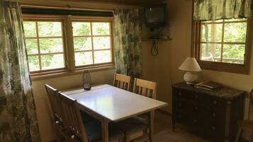 Una stanza con rivestimento in legno, un tavolo, sedie, una televisione e una lampada.