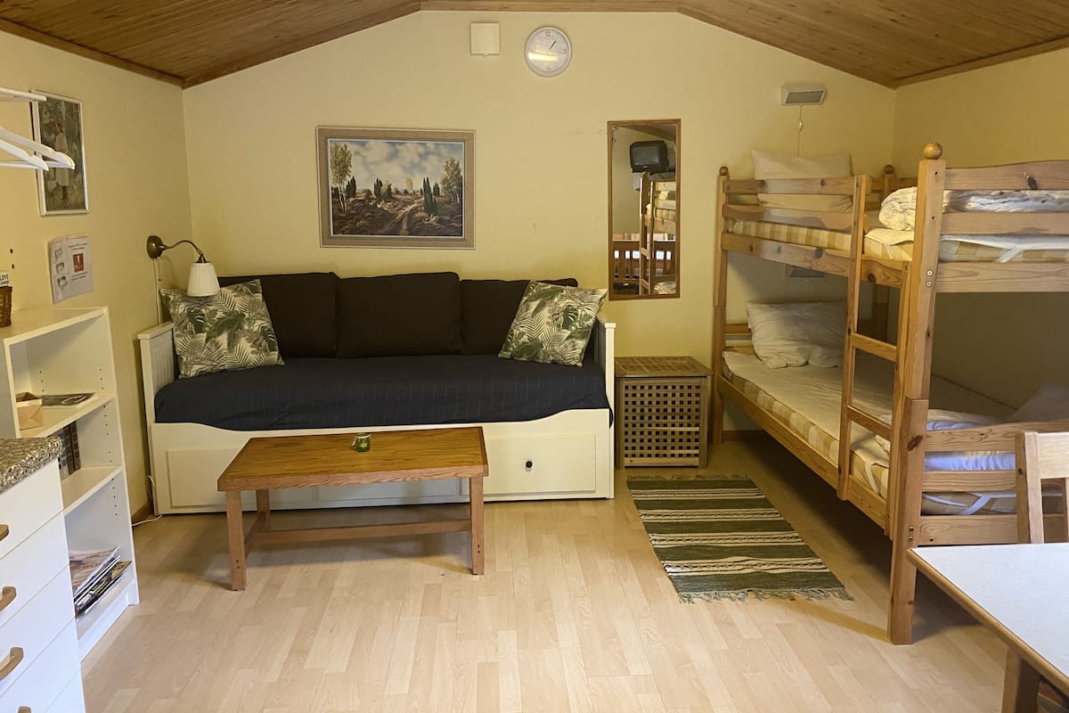 A cozy room with a sofa, a small table, bunk beds, and a painting on the wall.