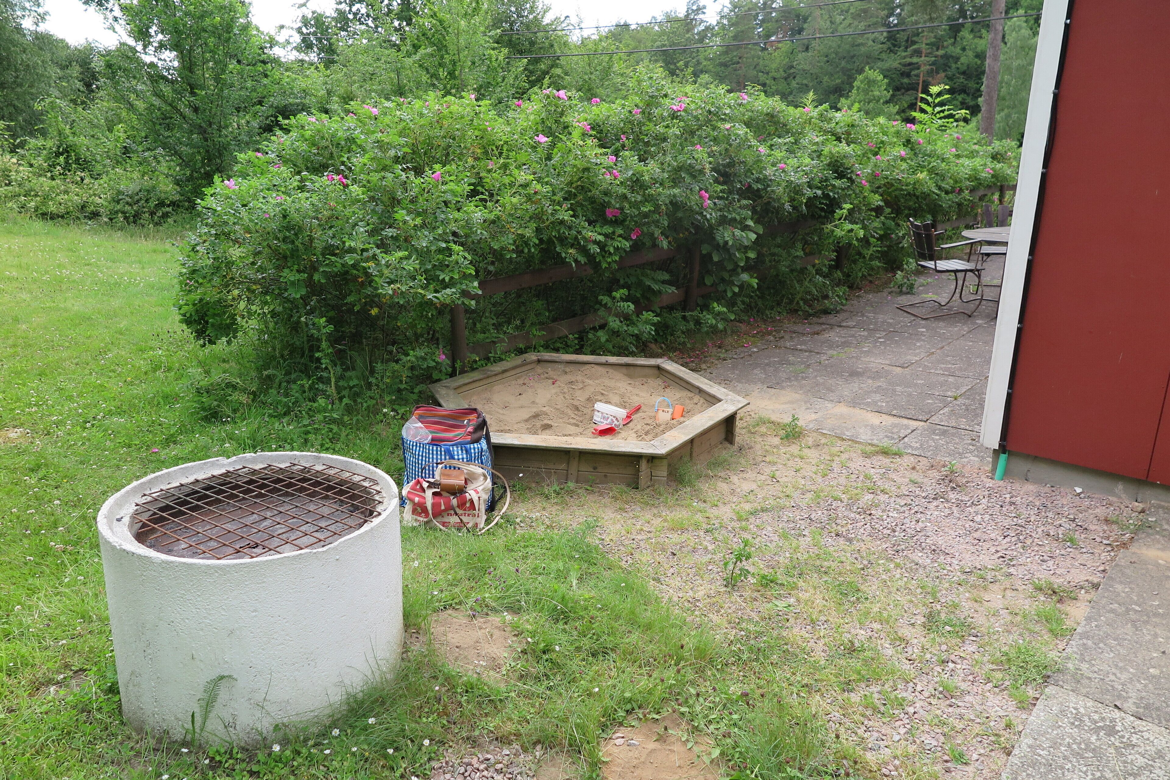 A garden with a wooden bench, a concrete planter, and a metal barrel.