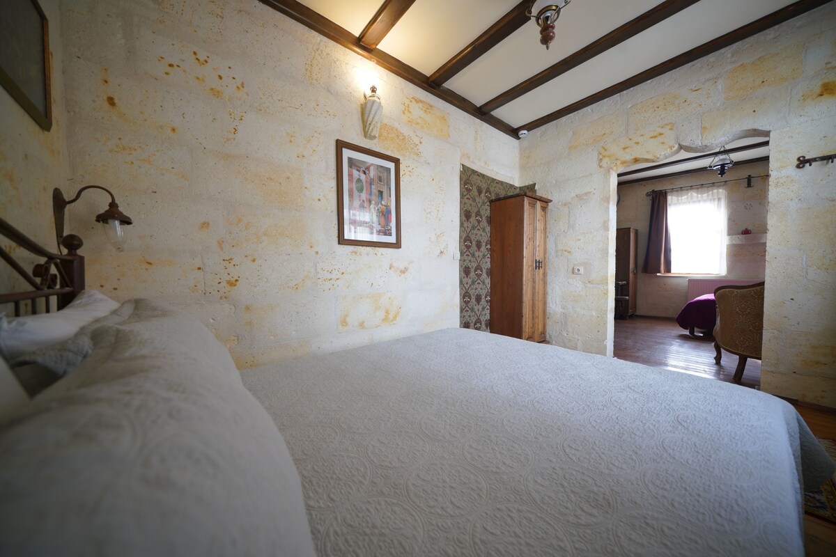 A bedroom with a large bed, a wooden wardrobe, and a framed picture on the wall.
