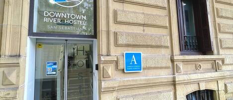 Un edificio con un cartel que dice 'Downtown River Hotel' y una señal azul en forma de 'A' que indica la habitación A.