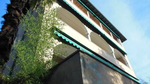 En bygning i traditionel arkitekturstil, med en balkon der har et grønt tag og hvide søjler.