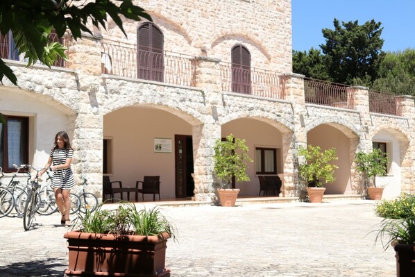A courtyard with stone walls, arched doorways, and potted plants. - Hotel Miramonti (Fasano)