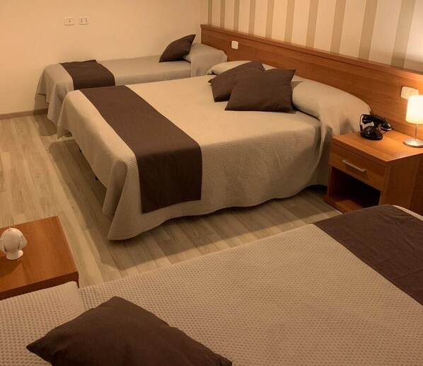 A hotel room with two beds, a nightstand with a lamp, and a small table with a decorative item.
