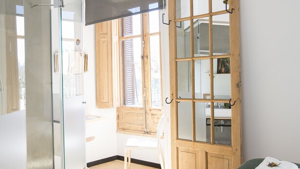 A modern bedroom with a glass shower, a wooden door, and a bed with towels. - Ibaia Et Arramak (San Sebastián)