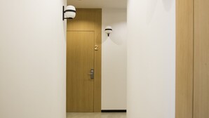 A narrow hallway with white walls, a wooden door labeled "2", and wall-mounted light fixtures. - Ibaia Et Arramak (San Sebastián)