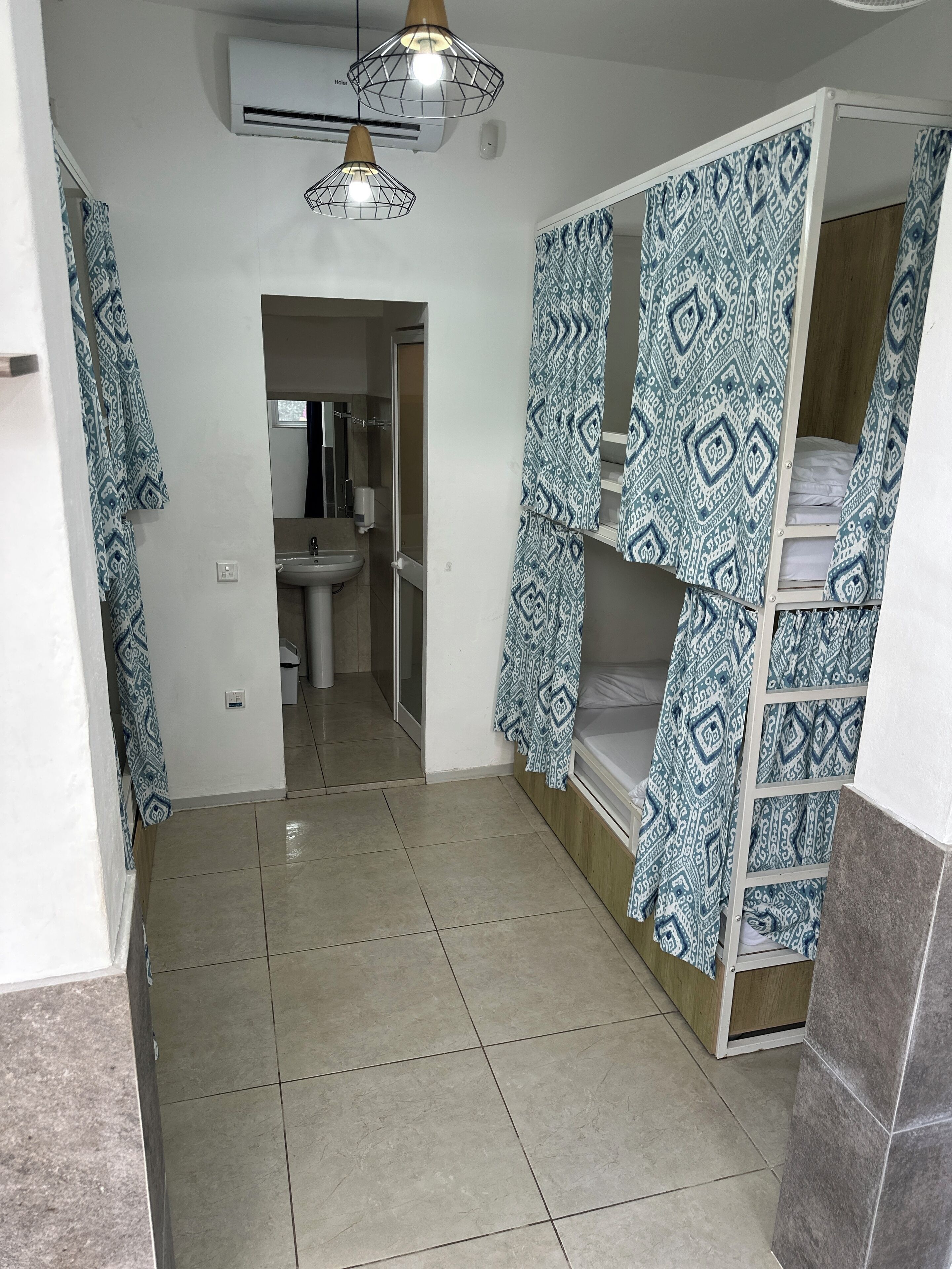 Une chambre avec un lit superposé, un lavabo et un miroir.