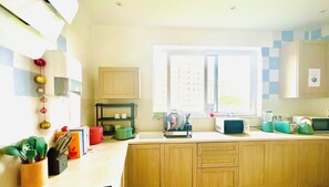 Una cocina con armarios de madera, un ventanal con vistas a edificios y varios electrodomésticos.