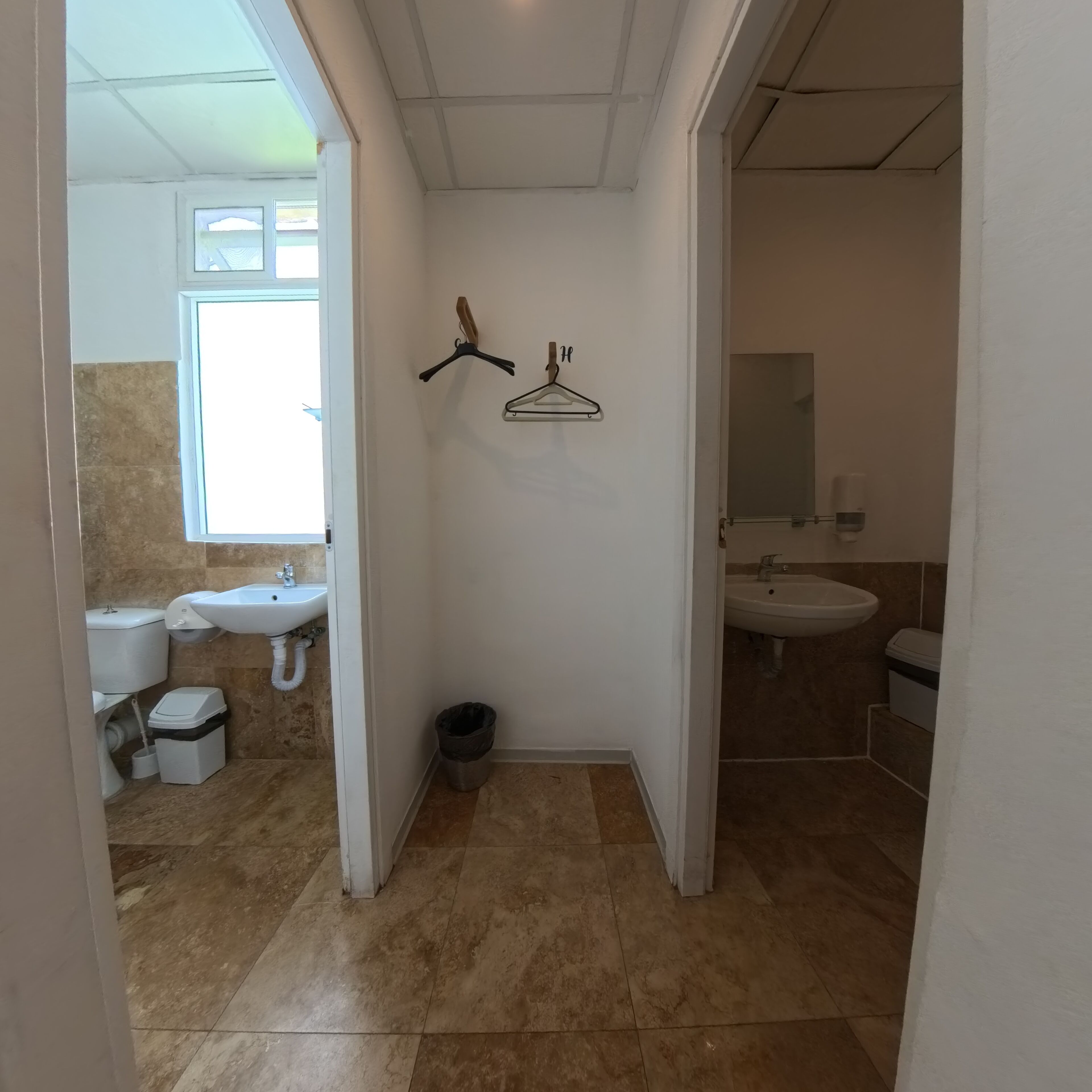 A bathroom with two sinks, a window, and a mirror.