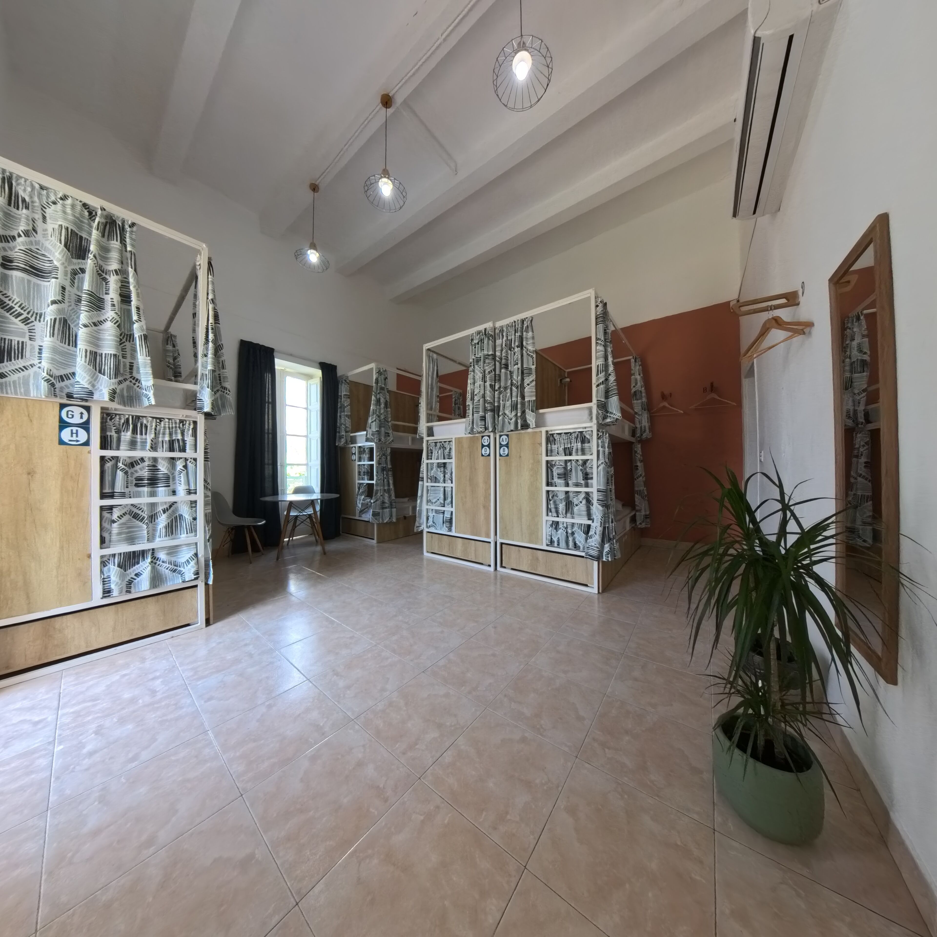 A spacious room with tiled floors, a dining area, and a large wardrobe with patterned curtains.