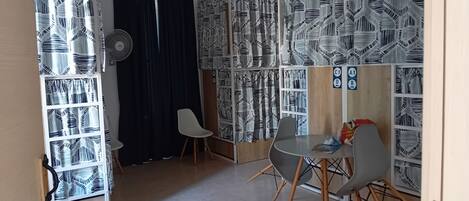 A room with a dining area, a black curtain, and patterned curtains on the walls.