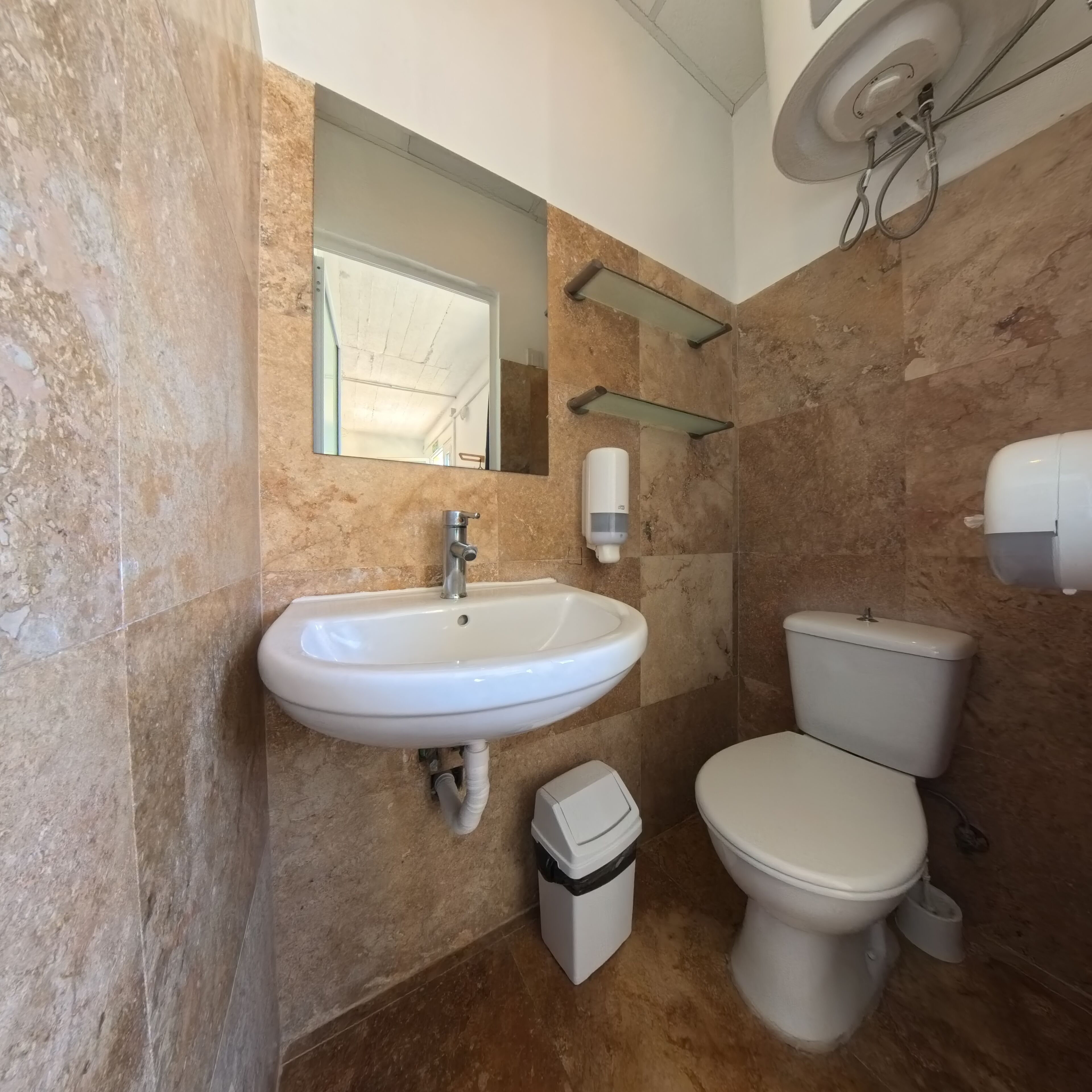 Une salle de bain avec un lavabo, des toilettes et un miroir.