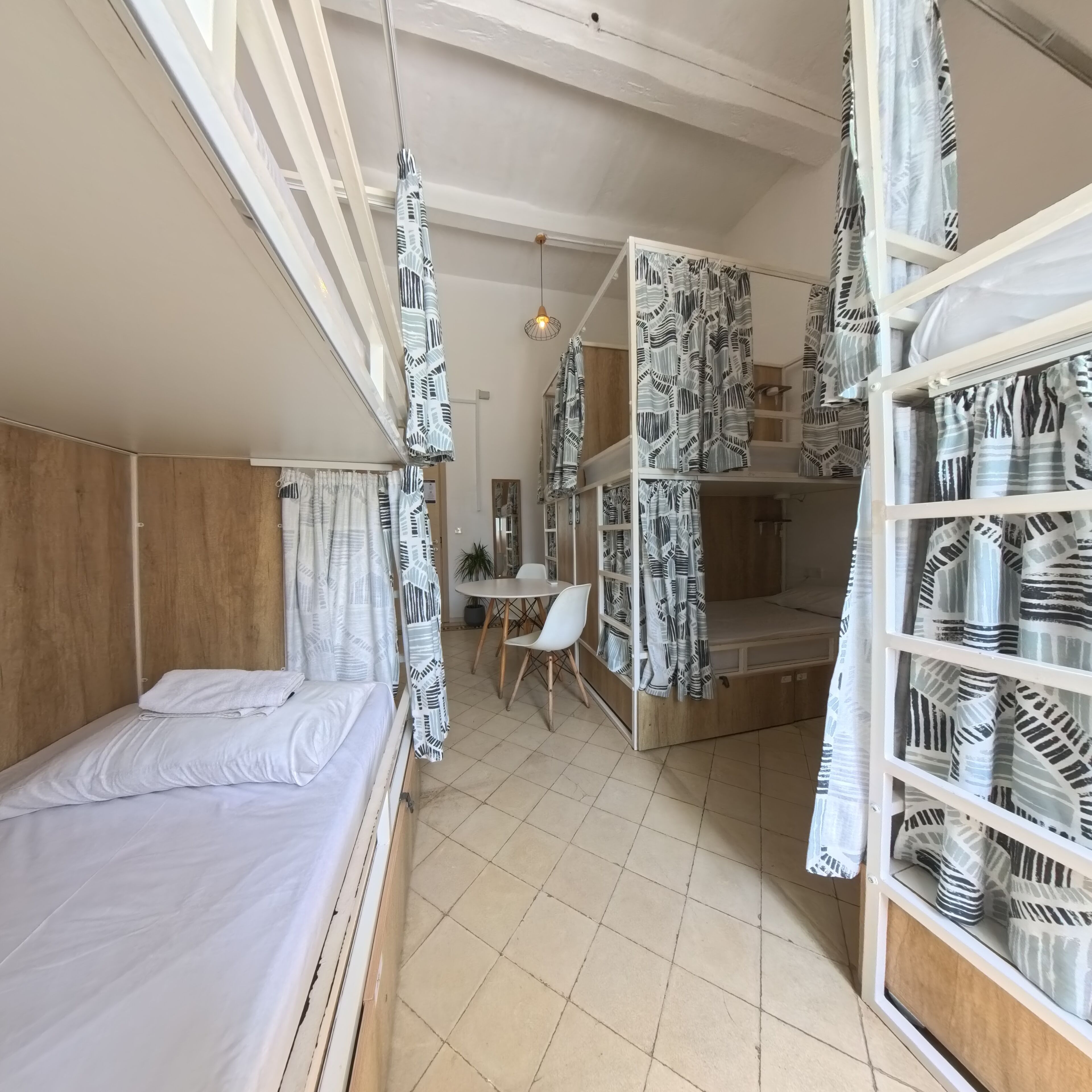 Une petite pièce comprenant un lit, une petite table et une chaise. Elle est équipée d’une étagère intégrée avec un espace de rangement.