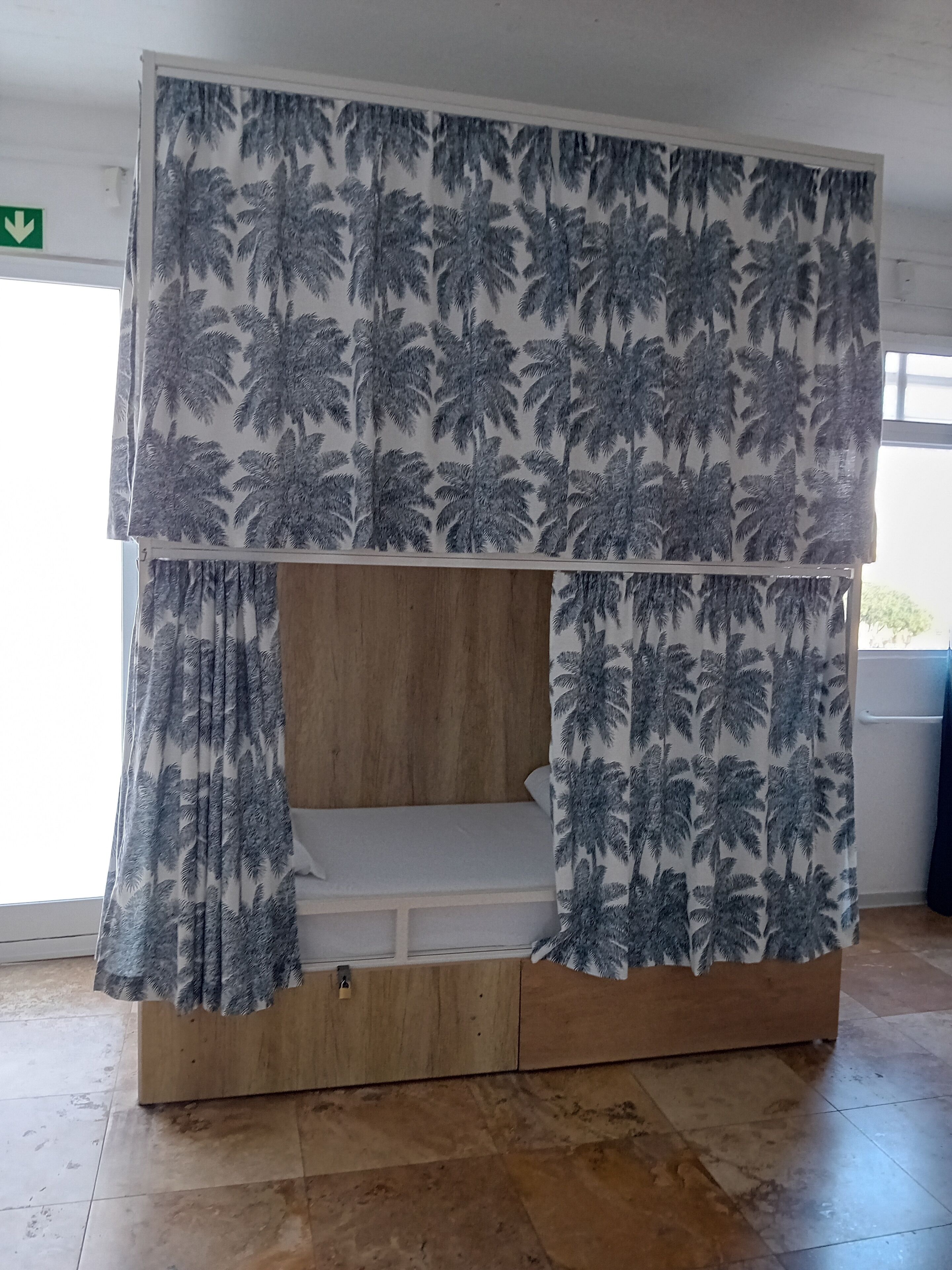 Una cama litera con estampado de hojas de palmera tropicales en las cortinas y el cabecero.