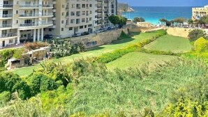 Una zona residencial costera con edificios de varios pisos, un campo de golf y vistas al mar.