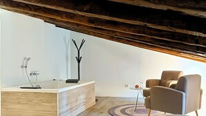 Una sala de estar moderna con piso de madera, un mueble empotrado de madera, un tapete redondo y una zona de estar con dos sillones.